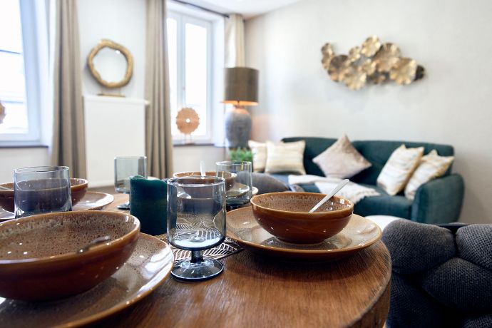 Gedeckter Esstisch mit Blick auf das gemütliche Sofa