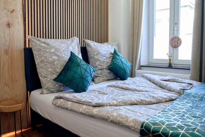 Doppelbett am Fenster mit warmen Holzdekor an den Wänden im Apartment Cozy forest