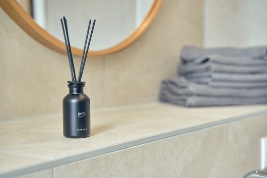 Detailaufnahme des Badezimmers von der Ablage mit Duftstäbchen, Spiegel und Handtüchern